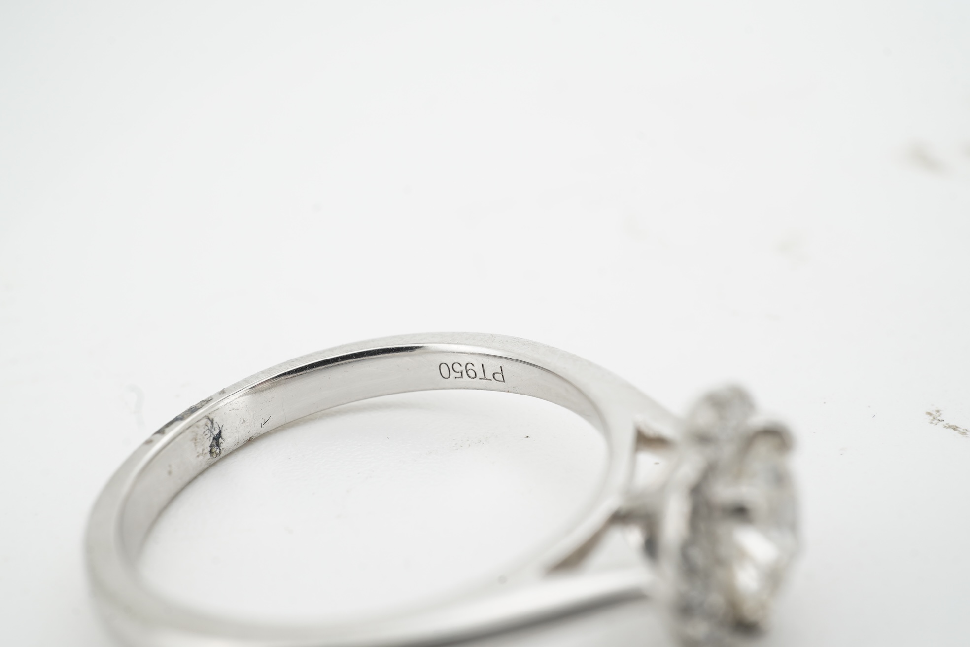 A diamond cluster ring, claw-set with a brilliant-cut diamond weighing approximately 0.70 carats, within a border of smaller brilliant-cut diamonds totalling approximately 0.10 carats, mounted in platinum, size M, Britis